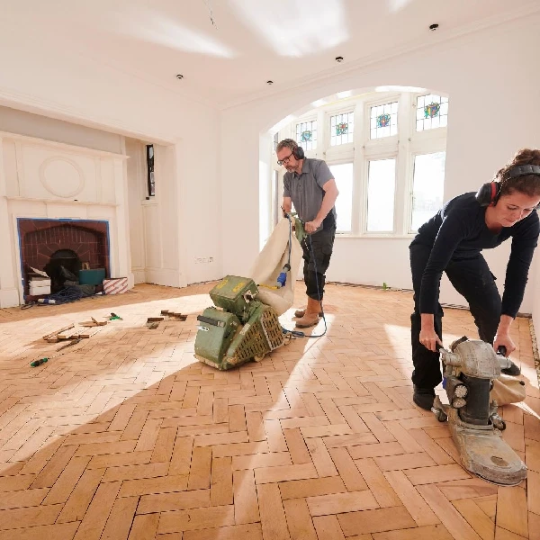 sanding a herringbone wood floor in a large